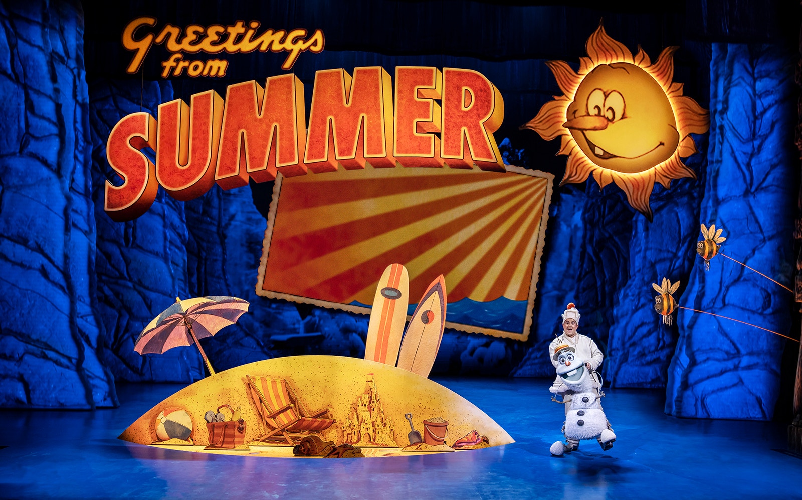 Stage scene from Frozen The Musical with Olaf in a summer setting.