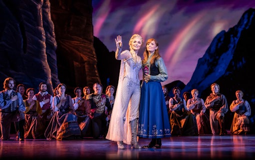Performers on stage during Frozen The Musical with a mountain backdrop.