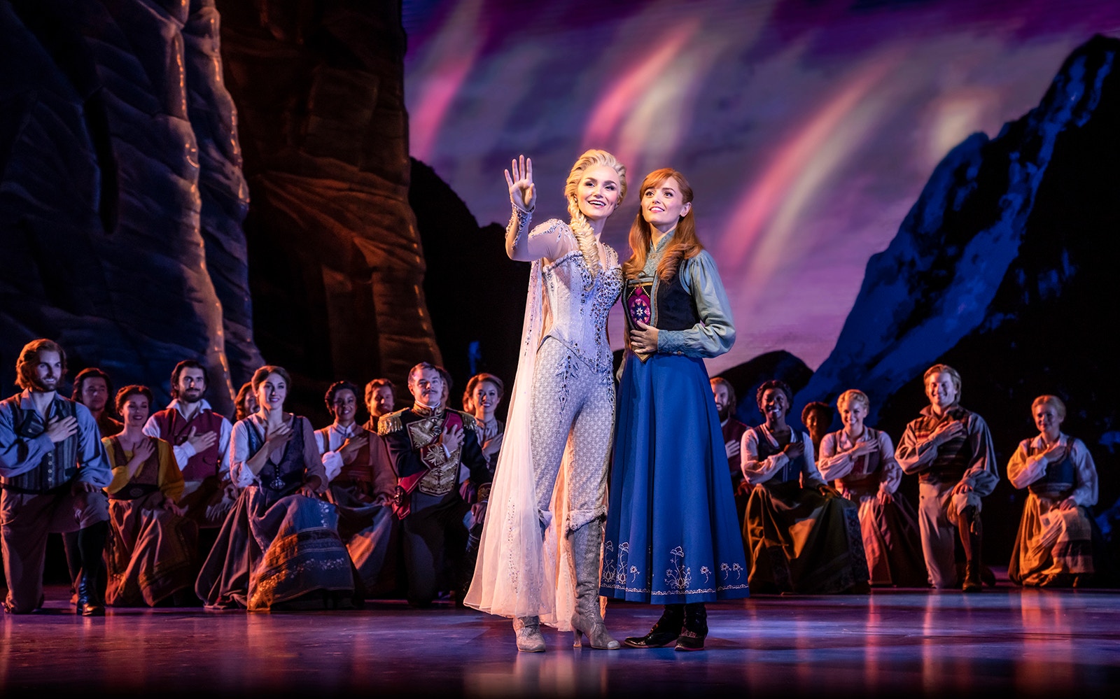 Performers on stage during Frozen The Musical with a mountain backdrop.