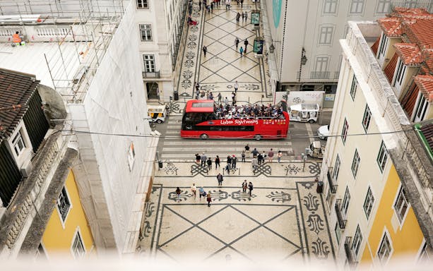 Lisbon sightseeing bus on a patterned street during a hop-on hop-off tour.