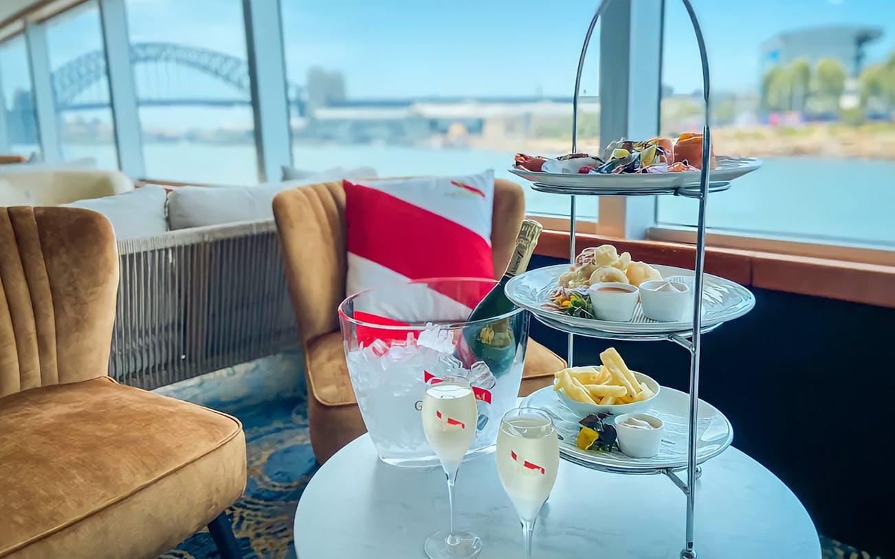 Champagne and snacks on a table at Mumm Champagne Harbour Bar with a view of Sydney Harbour Bridge.