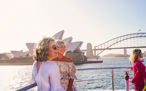 Women enjoying a boat tour with views of the Sydney Opera House and Harbour Bridge.