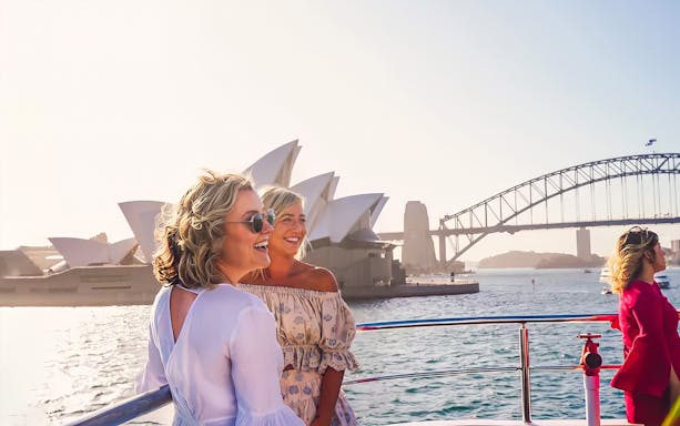 Women enjoying a boat tour with views of the Sydney Opera House and Harbour Bridge.