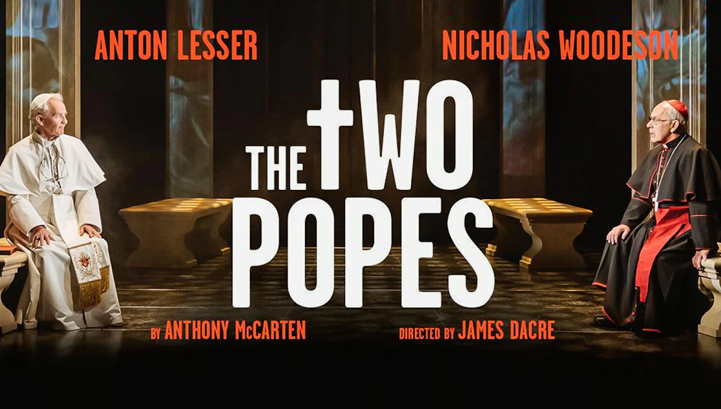 Two men in religious attire seated opposite each other in a dimly lit room, text reads "The Two Popes.