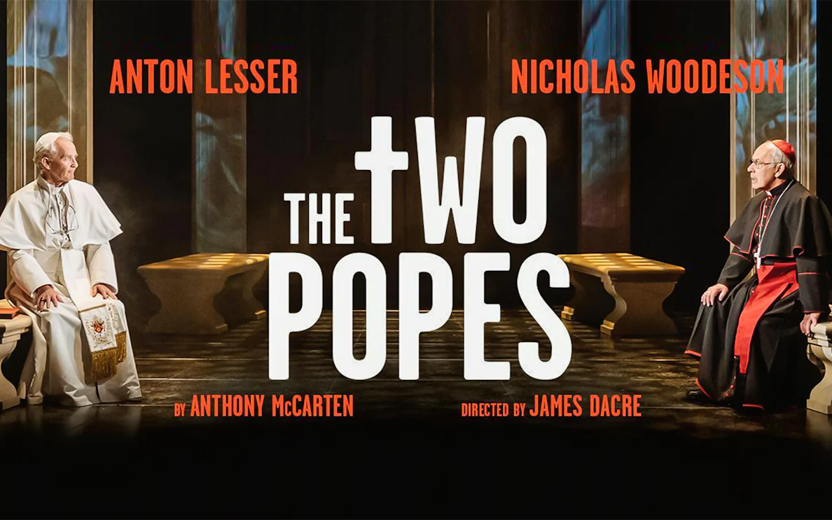 Two men in religious attire seated opposite each other in a dimly lit room, text reads "The Two Popes.