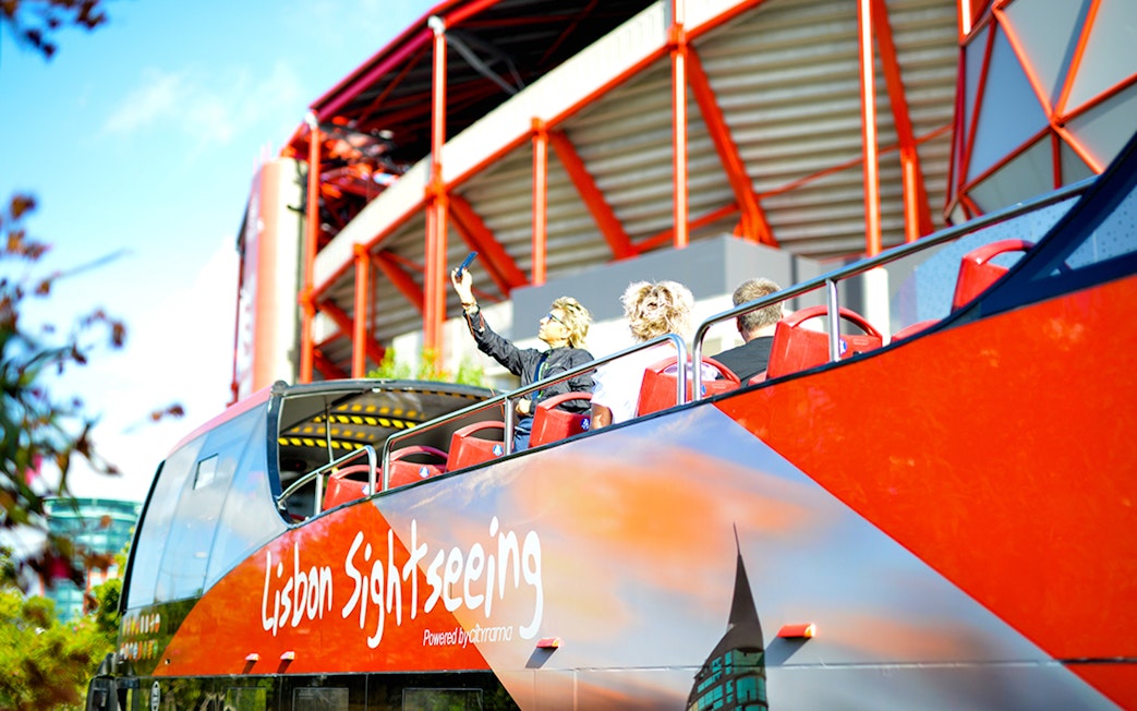 Open-top sightseeing bus near Lisbon stadium on hop-on-hop-off tour.