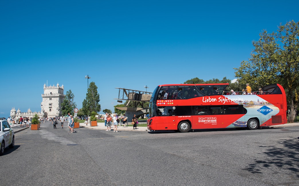 Red sightseeing bus near Belém Tower on Lisbon hop-on-hop-off tour.
