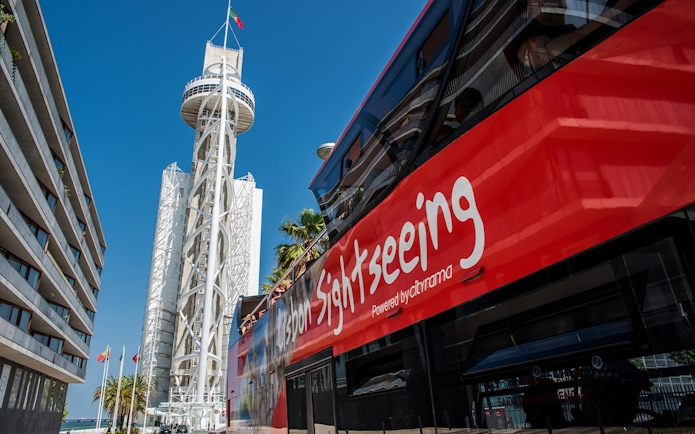 Lisbon sightseeing bus near Vasco da Gama Tower on hop-on-hop-off tour.