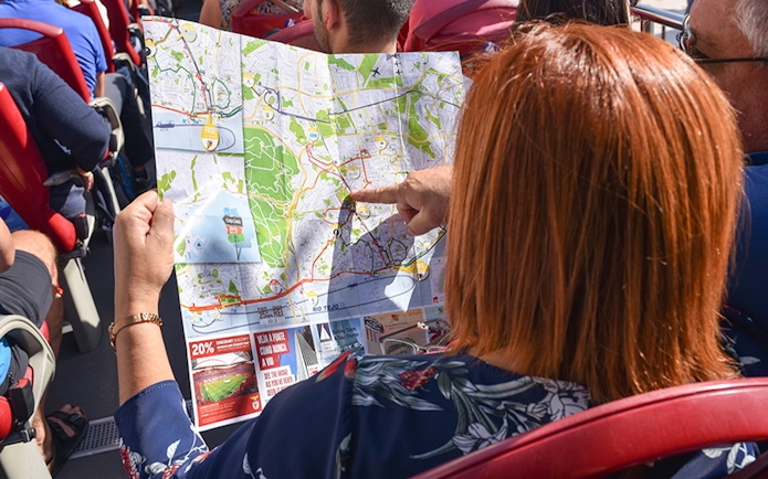 Person on Lisbon bus tour pointing at map route.