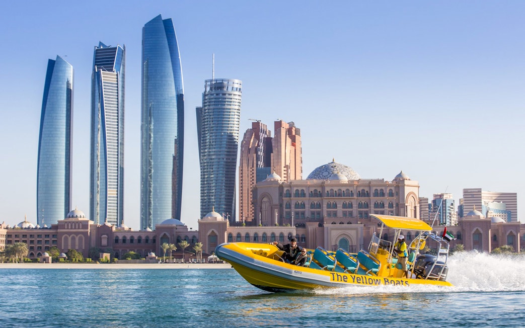 Yellow speedboat touring Abu Dhabi skyline with Etihad Towers in view.