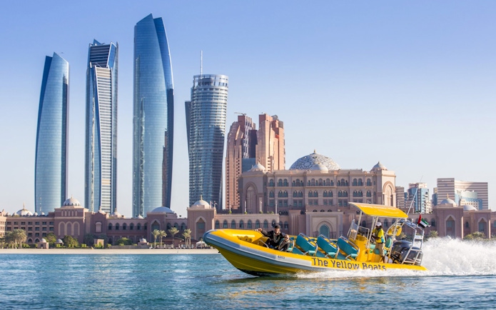 Yellow speedboat touring Abu Dhabi skyline with Etihad Towers in view.