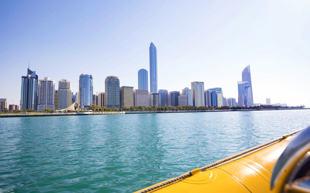 Abu Dhabi skyline viewed from a yellow speedboat on the water.