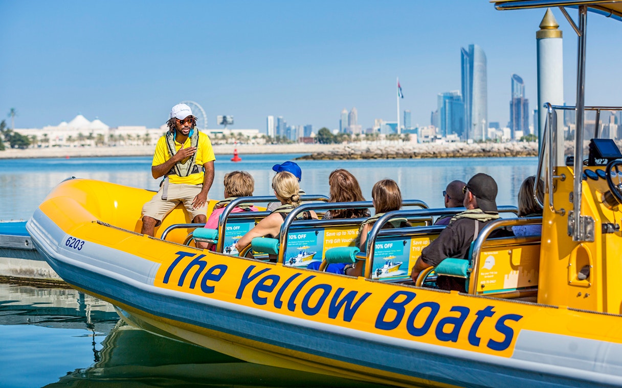 Sightseeing tour on a Yellow Boat in Abu Dhabi with city skyline in background.
