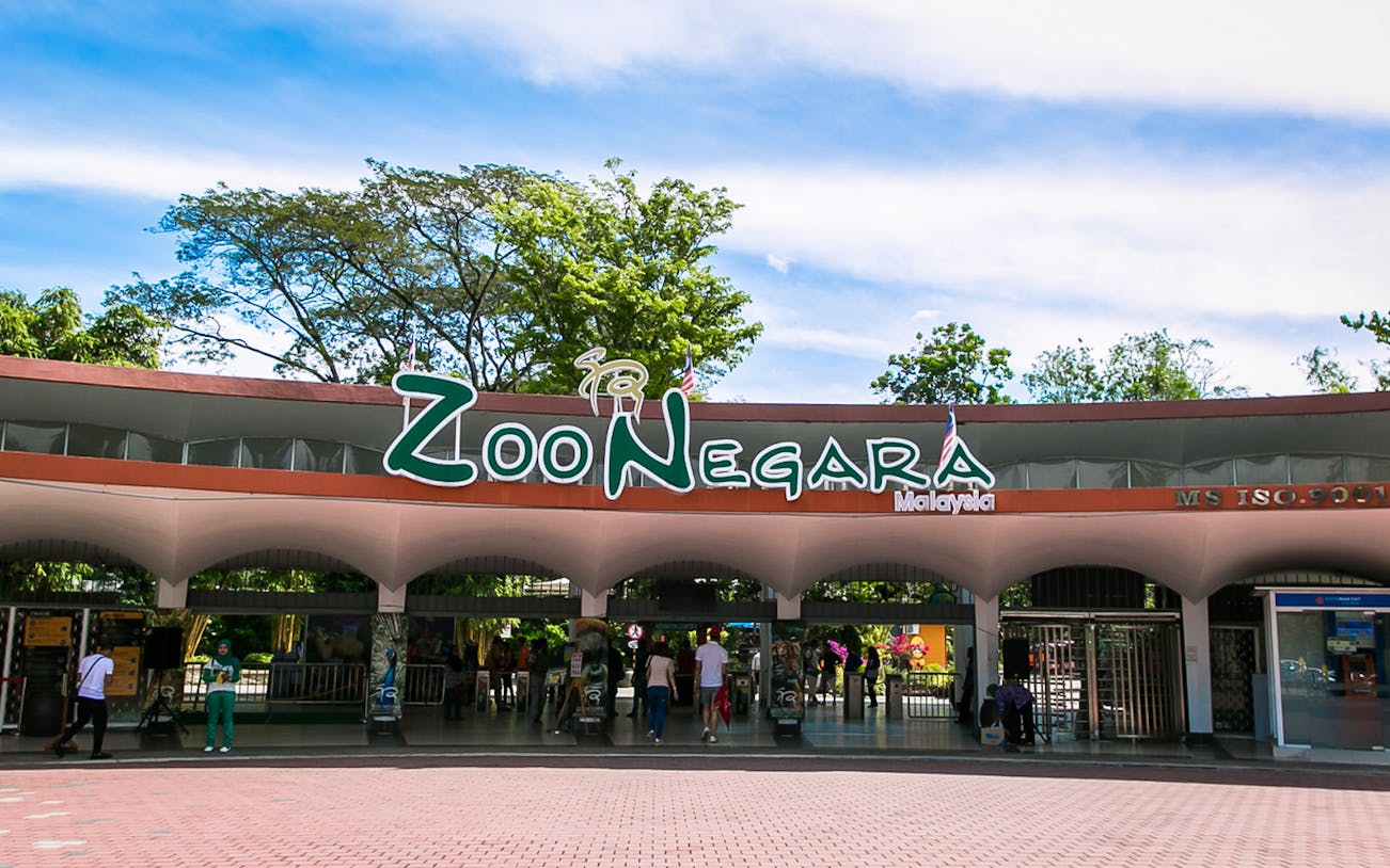 Zoo Negara Malaysia entrance with visitors and surrounding greenery.