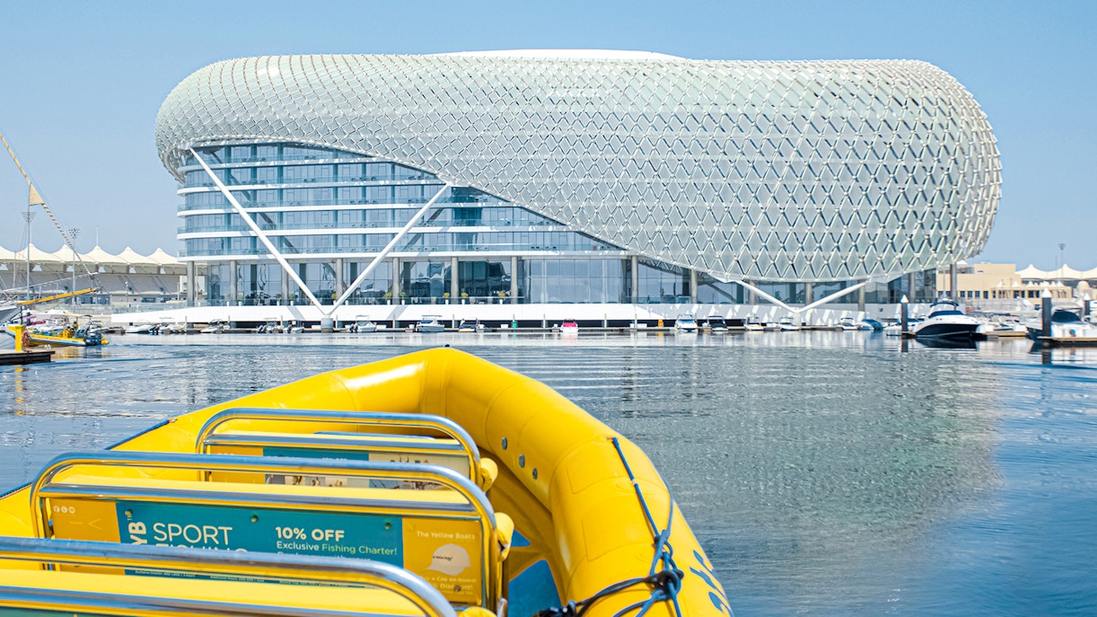 Yellow speedboat on Yas Island tour with modern architecture in the background.