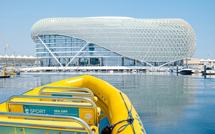 Yellow speedboat on Yas Island tour with modern architecture in the background.