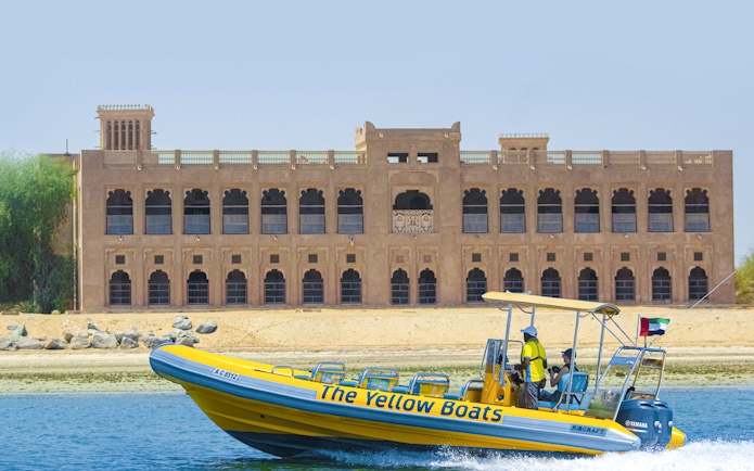 Yellow speedboat touring Yas Island with historic building in background.