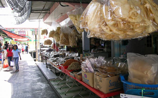 Street market in Kuala Lumpur with local snacks and shoppers.