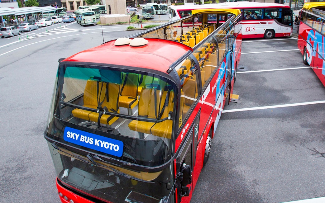 Kyoto sightseeing hop-on hop-off bus parked at a station with open-top seating.