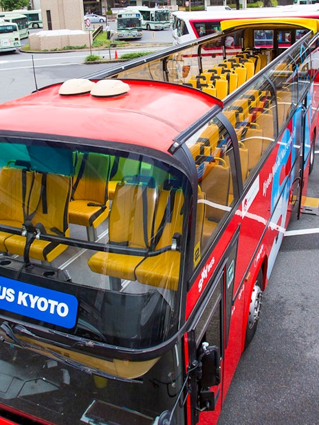 Kyoto sightseeing hop-on hop-off bus parked at a station with open-top seating.