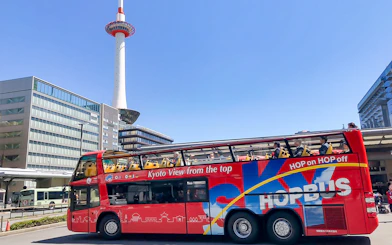 Kyoto Sky Hop Bus passing Kyoto Tower on a clear day.
