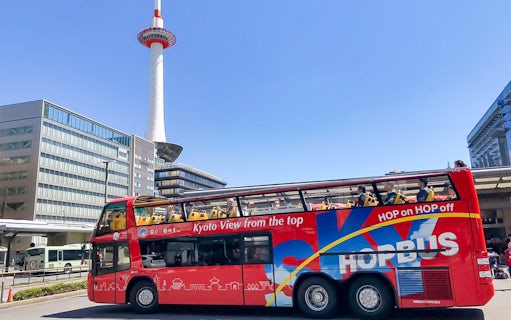 Kyoto Sky Hop Bus passing Kyoto Tower on a clear day.