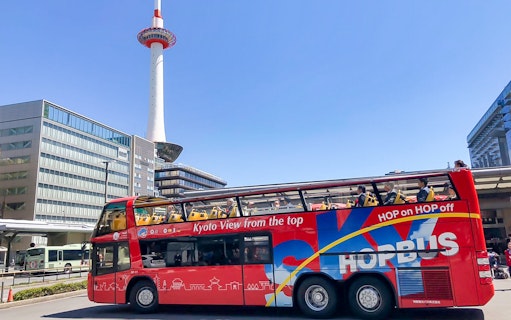 Kyoto Sky Hop Bus passing Kyoto Tower on a clear day.