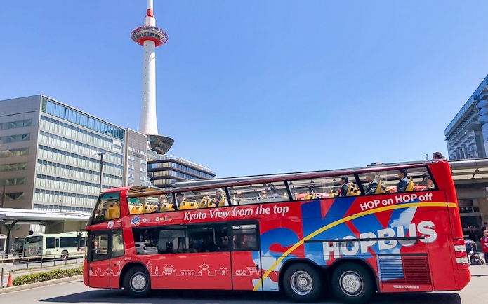 Kyoto Sky Hop Bus passing Kyoto Tower on a clear day.