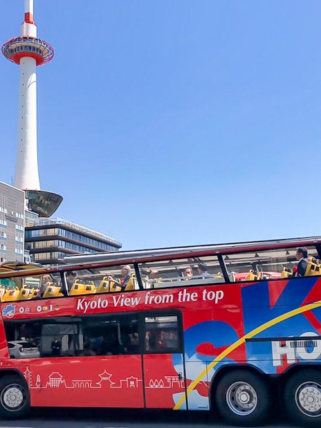 Kyoto Sky Hop Bus passing Kyoto Tower on a clear day.