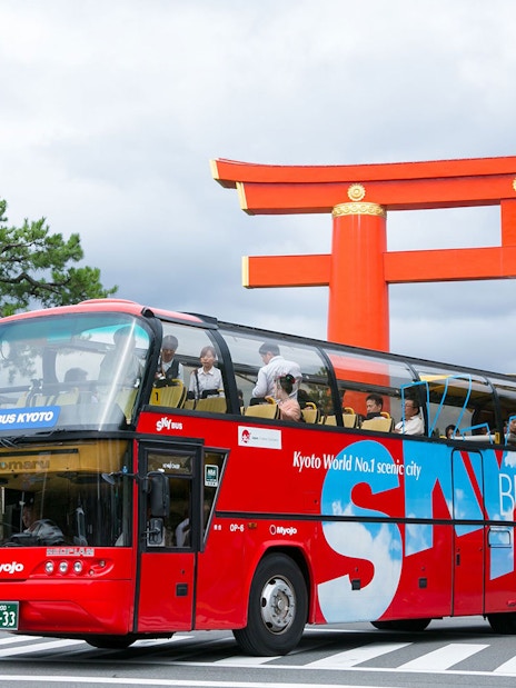 Sky Hop Bus passing a large red torii gate in Kyoto.