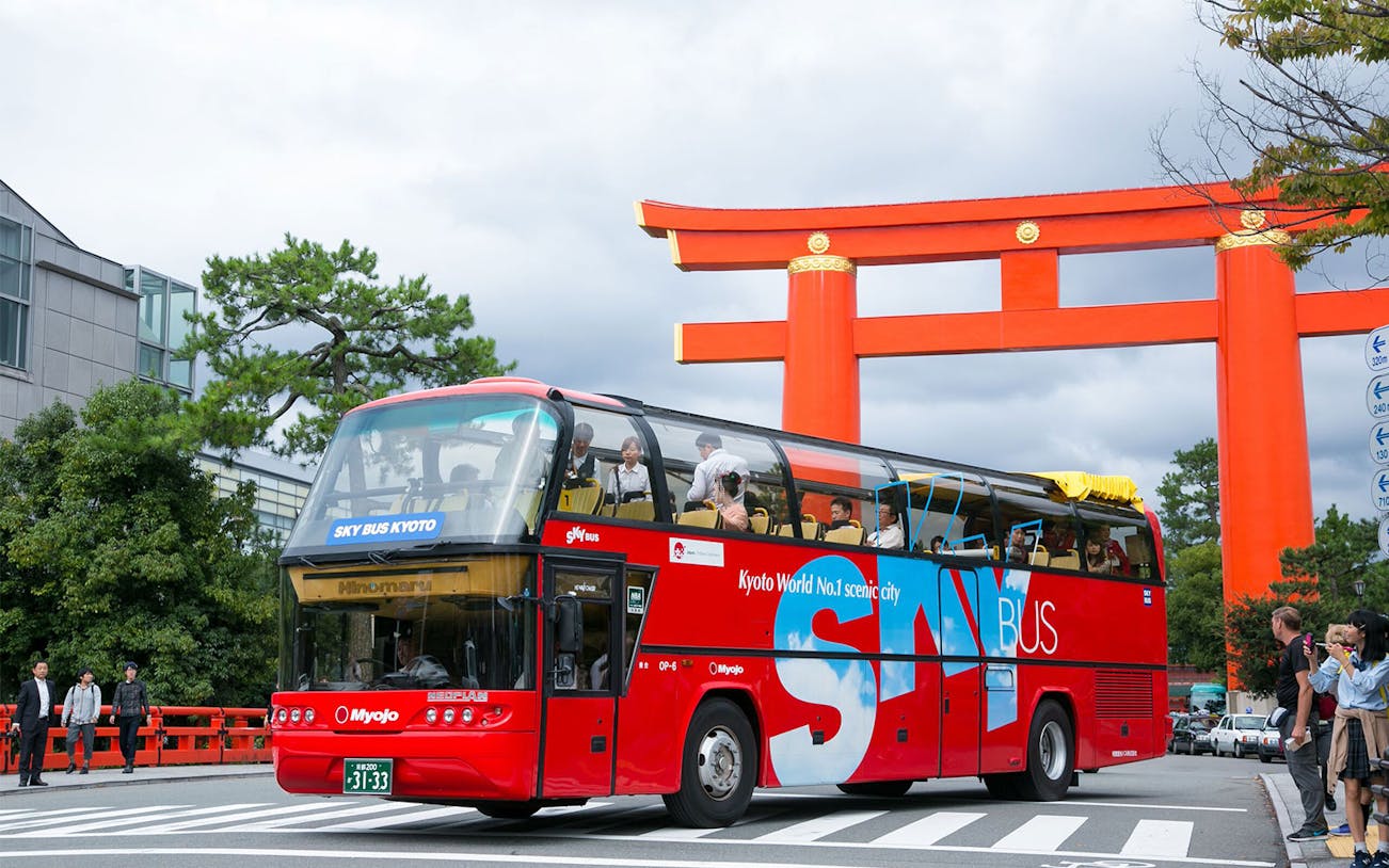 Sky Hop Bus passing a large red torii gate in Kyoto.