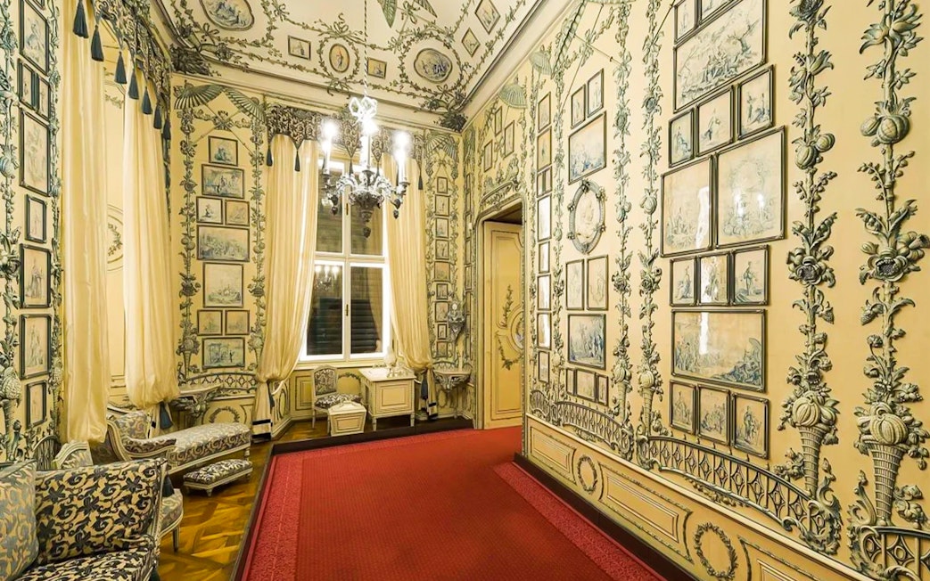 Ornate room with detailed wall art and chandelier in Schönbrunn Palace, Vienna.