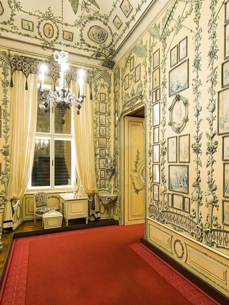 Ornate room with detailed wall art and chandelier in Schönbrunn Palace, Vienna.