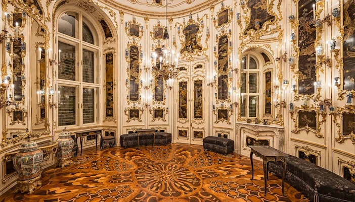 Ornate room interior at Schönbrunn Palace, Vienna, featuring intricate wood flooring and decorative walls.