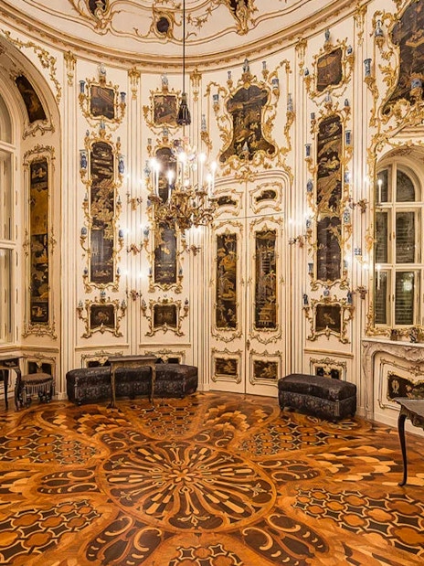 Ornate room interior at Schönbrunn Palace, Vienna, featuring intricate wood flooring and decorative walls.