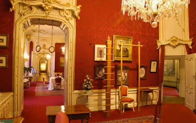 Empress Sisi's Vienna tour, ornate red room with chandeliers and historical portraits.
