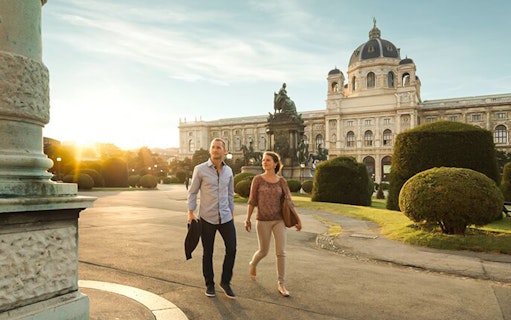 Couple walking near Vienna's Kunsthistorisches Museum at sunset.