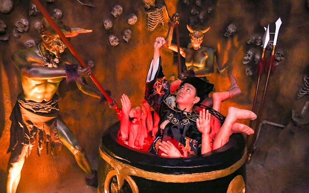 Man in traditional attire surrounded by demons in Ghost Museum Melaka exhibit.