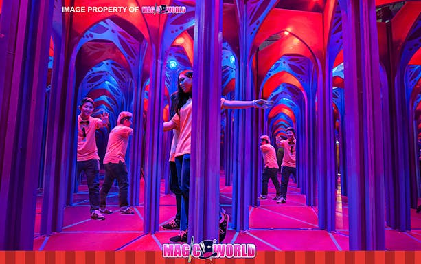 Visitors exploring a colorful mirror maze at Magic World Penang.