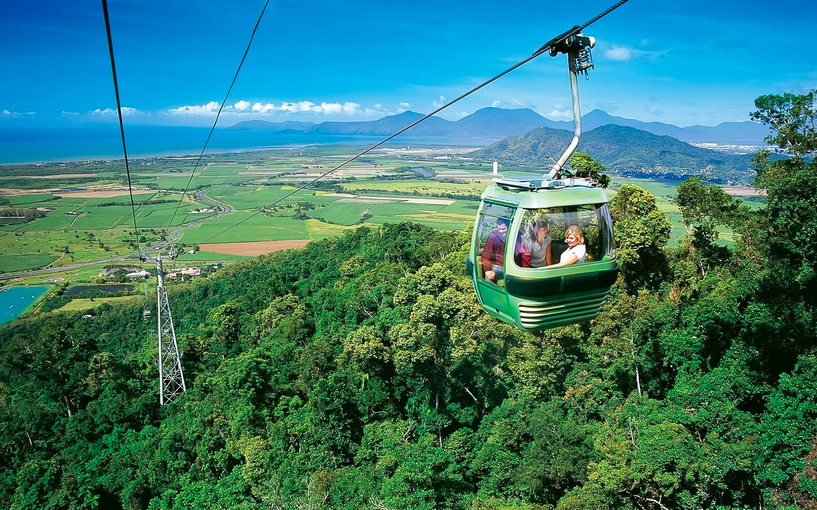 Skyrail gondola over rainforest with views of Cairns and mountains in the background.