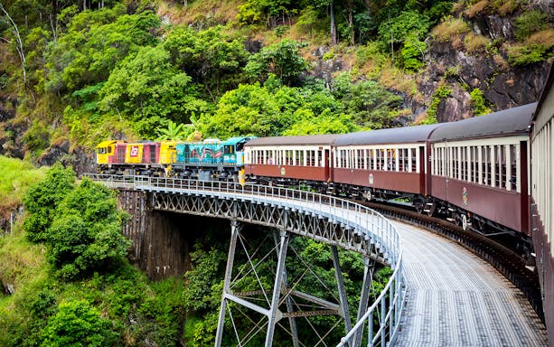 Kuranda Scenic Railway crossing a bridge through lush rainforest near Cairns, Australia.