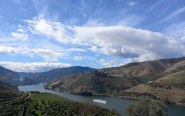 Cruise ship on Douro River with terraced vineyards in Douro Valley, Portugal.