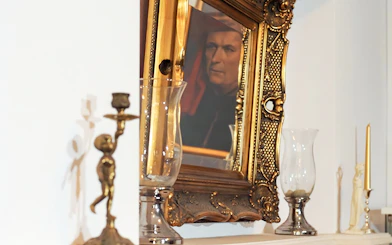 Reflection of a portrait in an ornate gold frame near candlesticks, related to Evening Chopin Piano Concert.