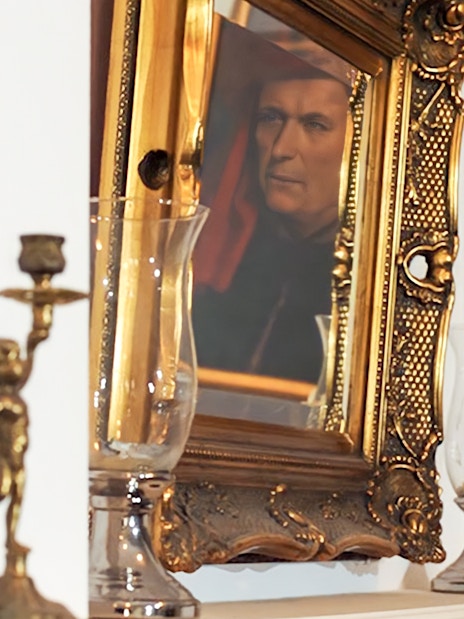 Reflection of a portrait in an ornate gold frame near candlesticks, related to Evening Chopin Piano Concert.