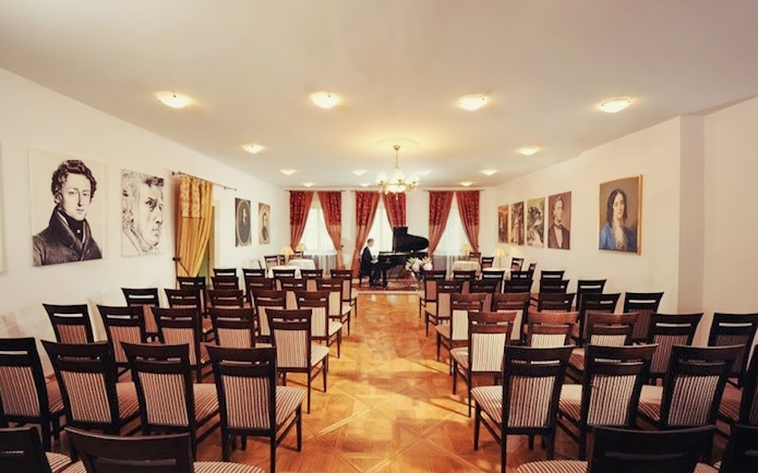 Chopin piano concert hall with portraits and empty chairs.