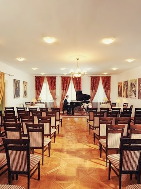 Chopin piano concert hall with portraits and empty chairs.