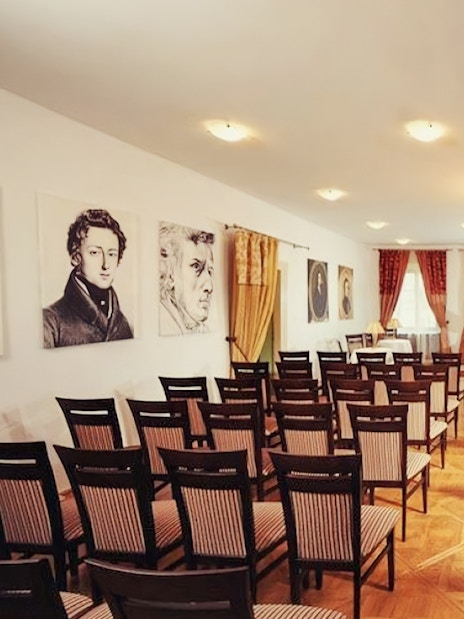 Chopin piano concert hall with portraits and empty chairs.