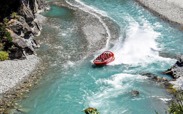 Jet boat on turquoise river during Queenstown to Christchurch tour via Mt Cook and Lake Tekapo.