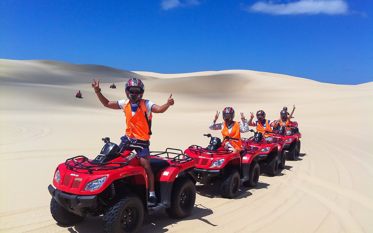 Group riding quad bikes on Stockton Beach sand dunes.