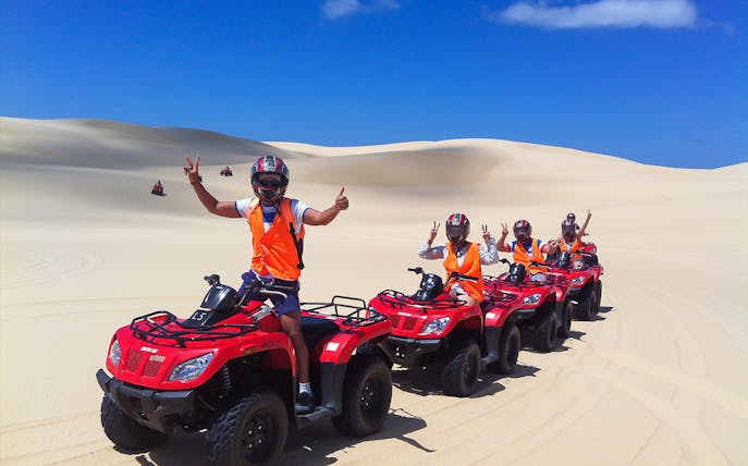 Group riding quad bikes on Stockton Beach sand dunes.